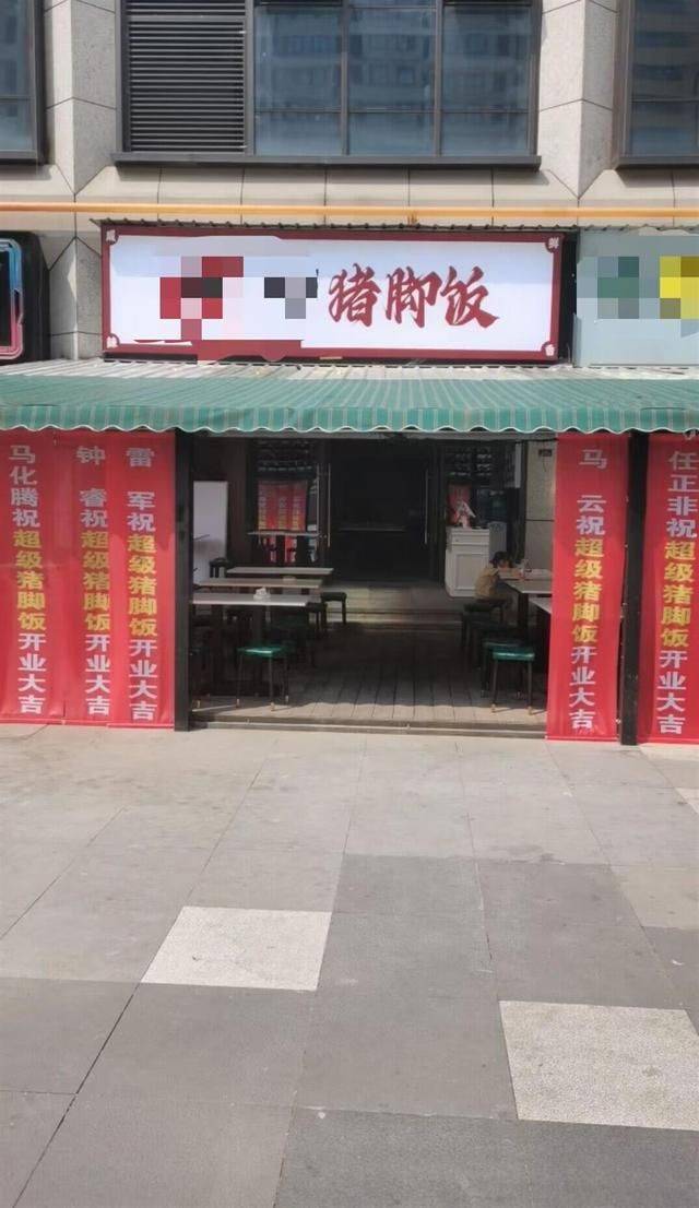 有一家猪脚饭餐馆开业,店门口摆满了花篮,还挂了多条祝贺横幅