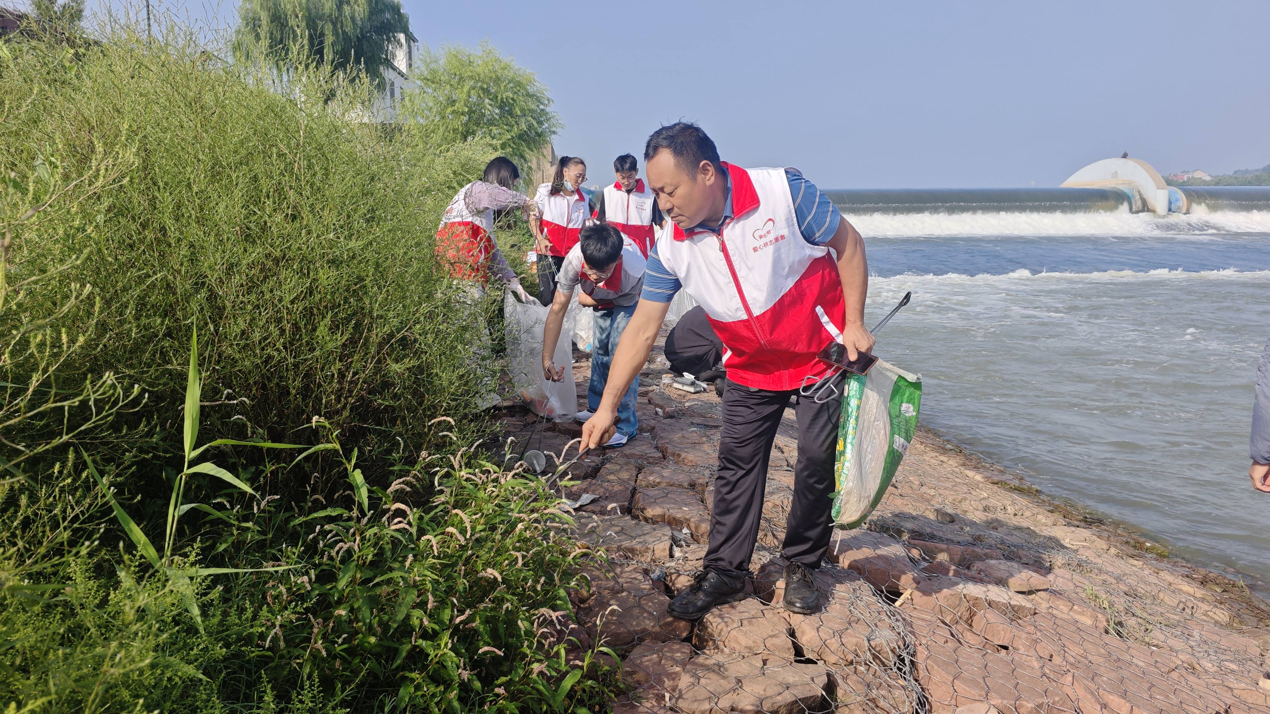 捡垃圾活动中,志愿者们身穿"红马甲",手持垃圾袋,垃圾夹等工具,在伊