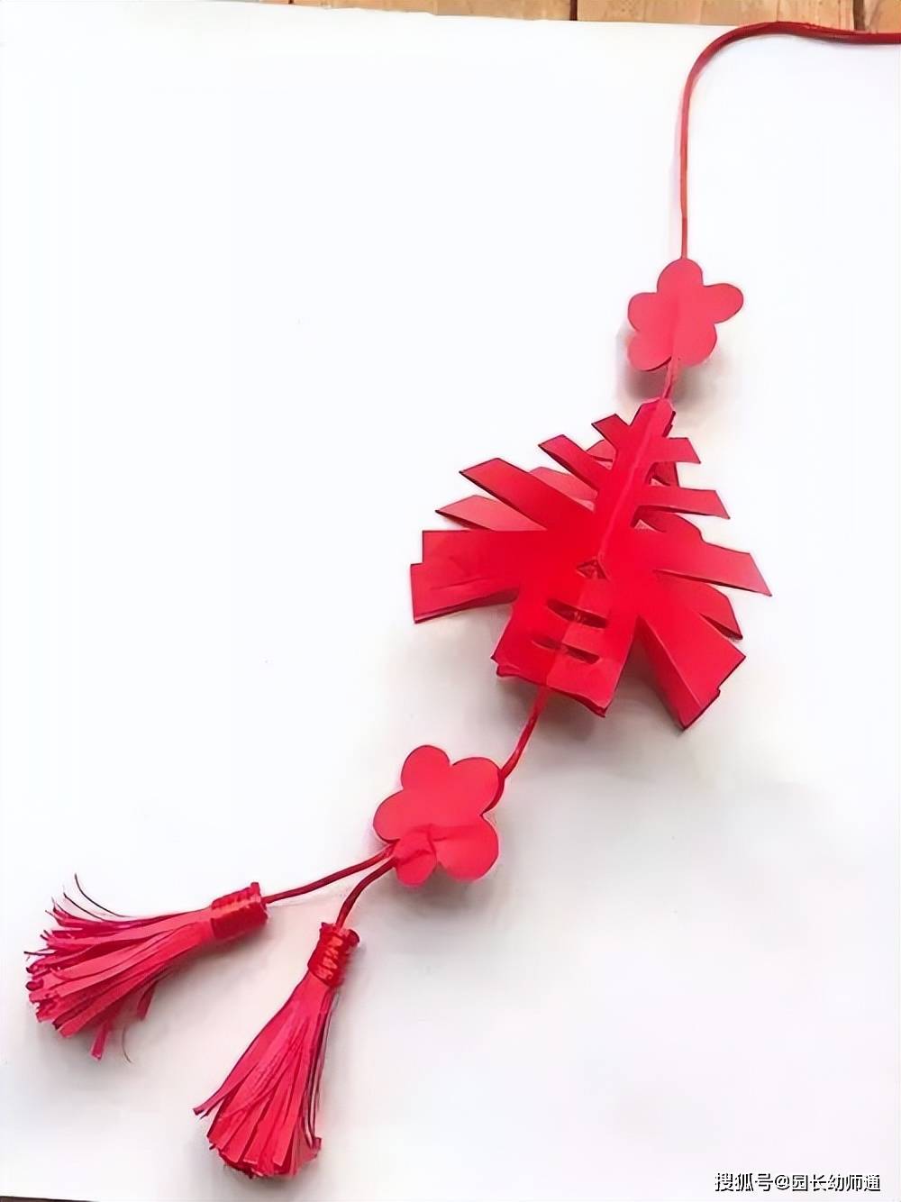 春字吊饰先在两个底部的中心钻孔穿红线,然后将两只纸杯的条状对应粘