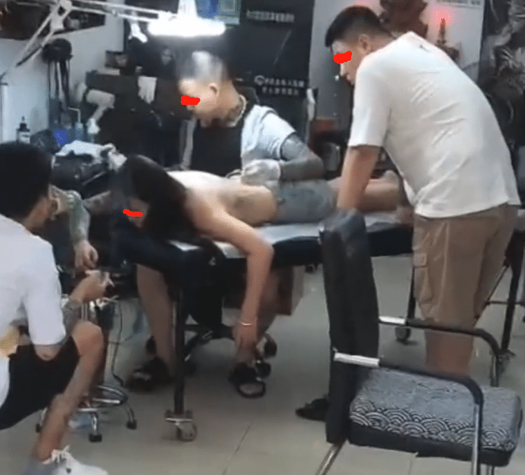 身体略微弯曲,和纹身师傅正好相对,同样眼睛直直的盯着女子的背后,不