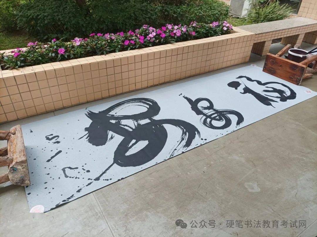 在巨幅水写布上,学生们轮番体验毛笔,地书笔,大椽笔,感受以水代墨的五