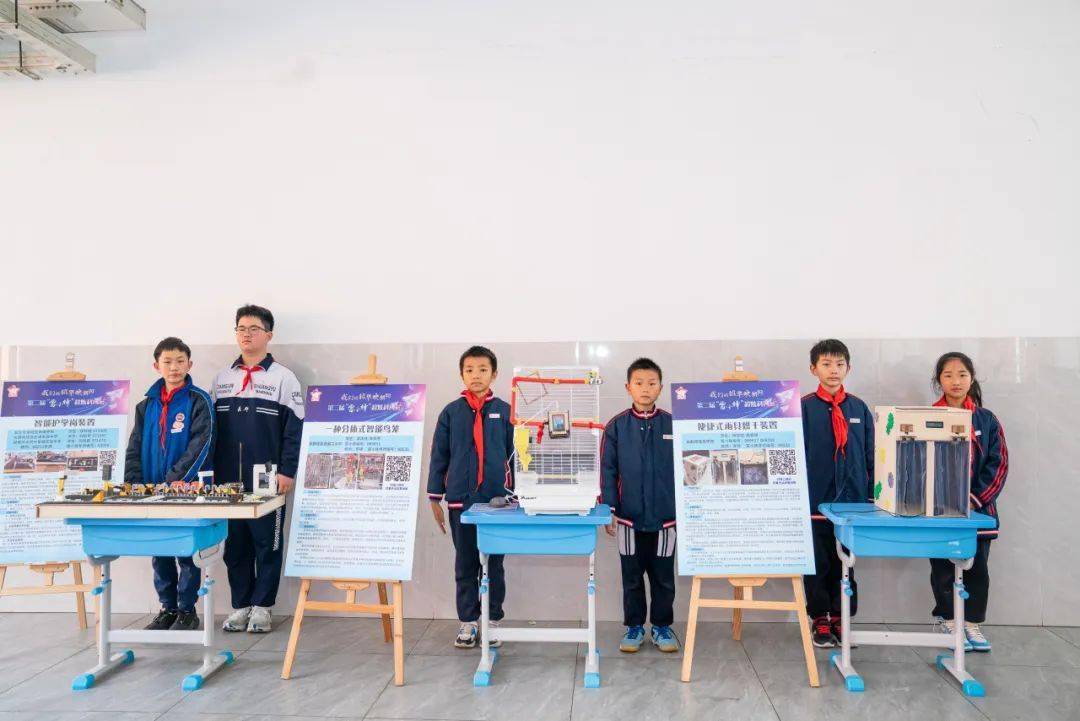 在一款名为"智能护学岗"的装置前,三名身穿不同学校校服的同学们热心