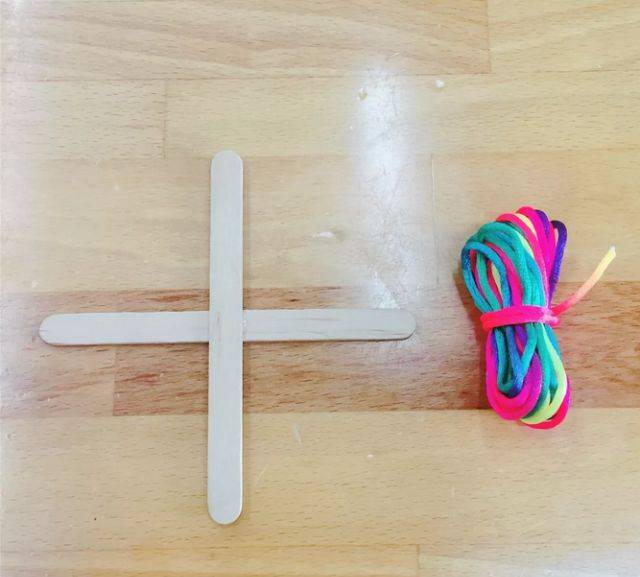 在木棍交叉的地方,将毛线开始在一根棍子上绕一圈将线头包裹起来.
