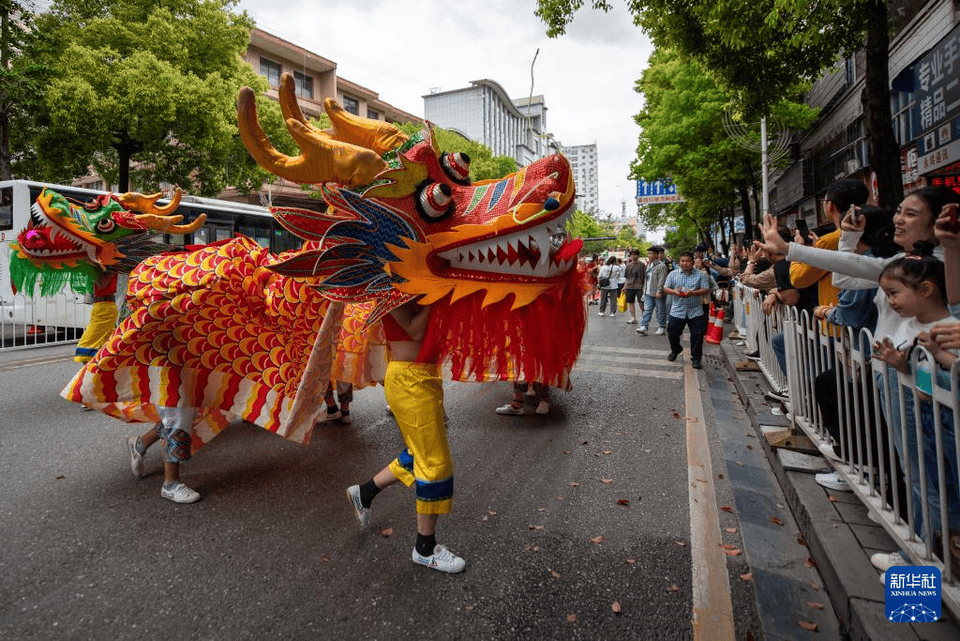 4月20日,在湖北省来凤县城区街头,民间艺人在表演地龙灯.