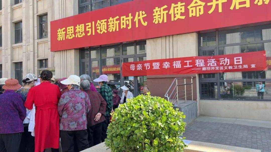 活动现场悬挂"母亲节暨幸福工程活动日"条幅,工作人员向过往居民发放