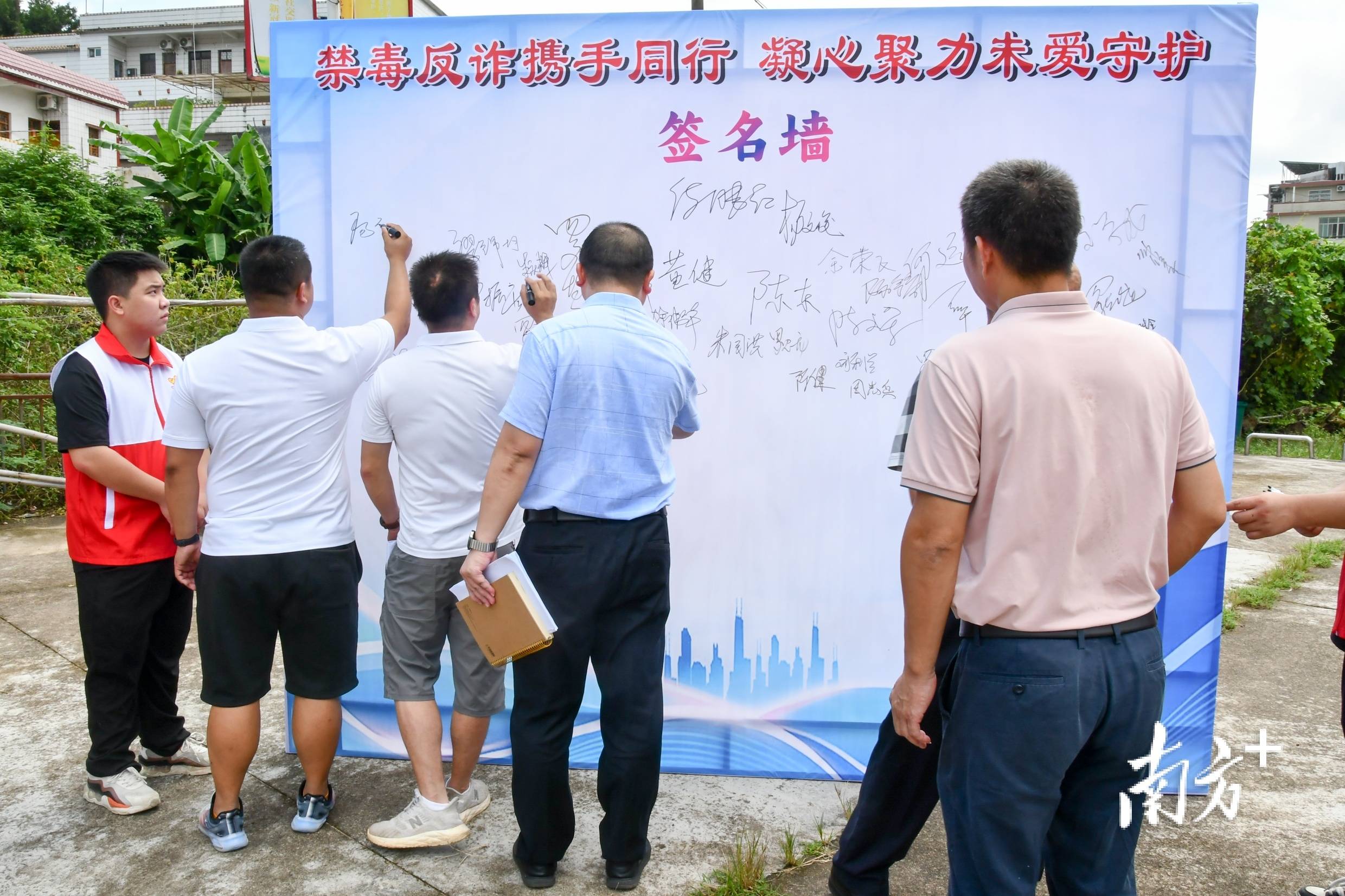 参会人员在禁毒反诈签名墙上签名,以己之名宣誓参与禁毒,反诈的决心