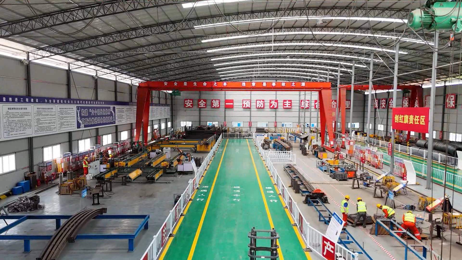 在邵永铁路项目3号钢构件加工场,工人正操纵智能设备生产钢拱架,钢筋